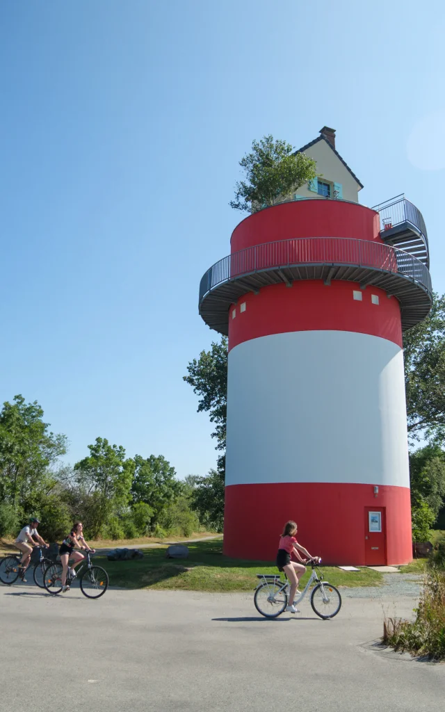 3 personnes à vélo qui passent devant la Villa Cheminee Oeoeuvre Du Parcours Estuaire Nantes Saint Nazaire Cadre Large