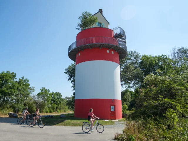 3 personnes à vélo qui passent devant la Villa Cheminee Oeoeuvre Du Parcours Estuaire Nantes Saint Nazaire Cadre Large