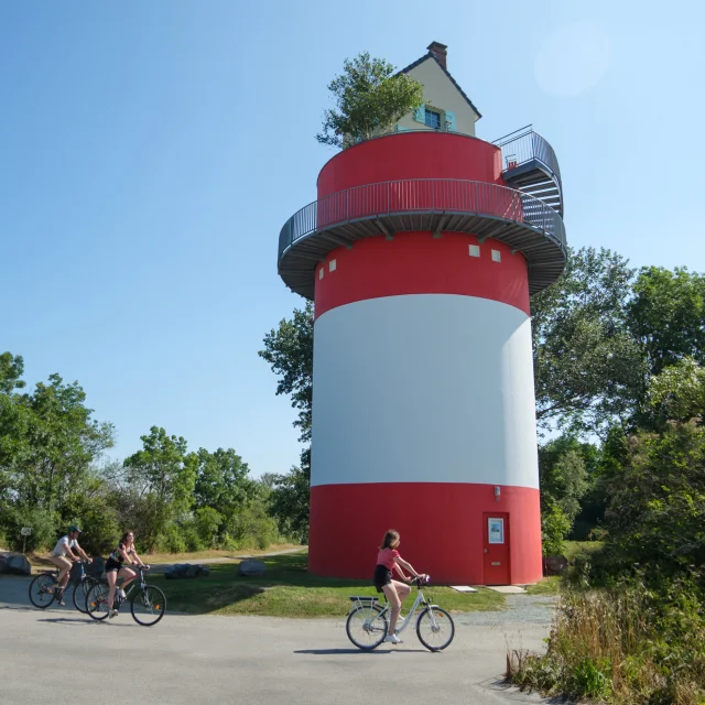 3 personnes à vélo qui passent devant la Villa Cheminee Oeoeuvre Du Parcours Estuaire Nantes Saint Nazaire Cadre Large