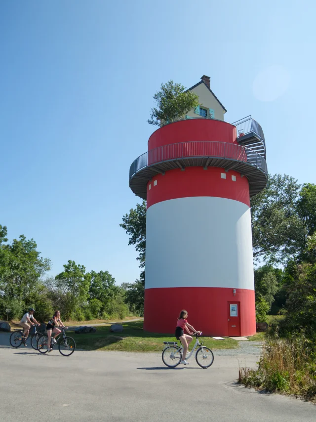 3 personnes à vélo qui passent devant la Villa Cheminee Oeoeuvre Du Parcours Estuaire Nantes Saint Nazaire Cadre Large